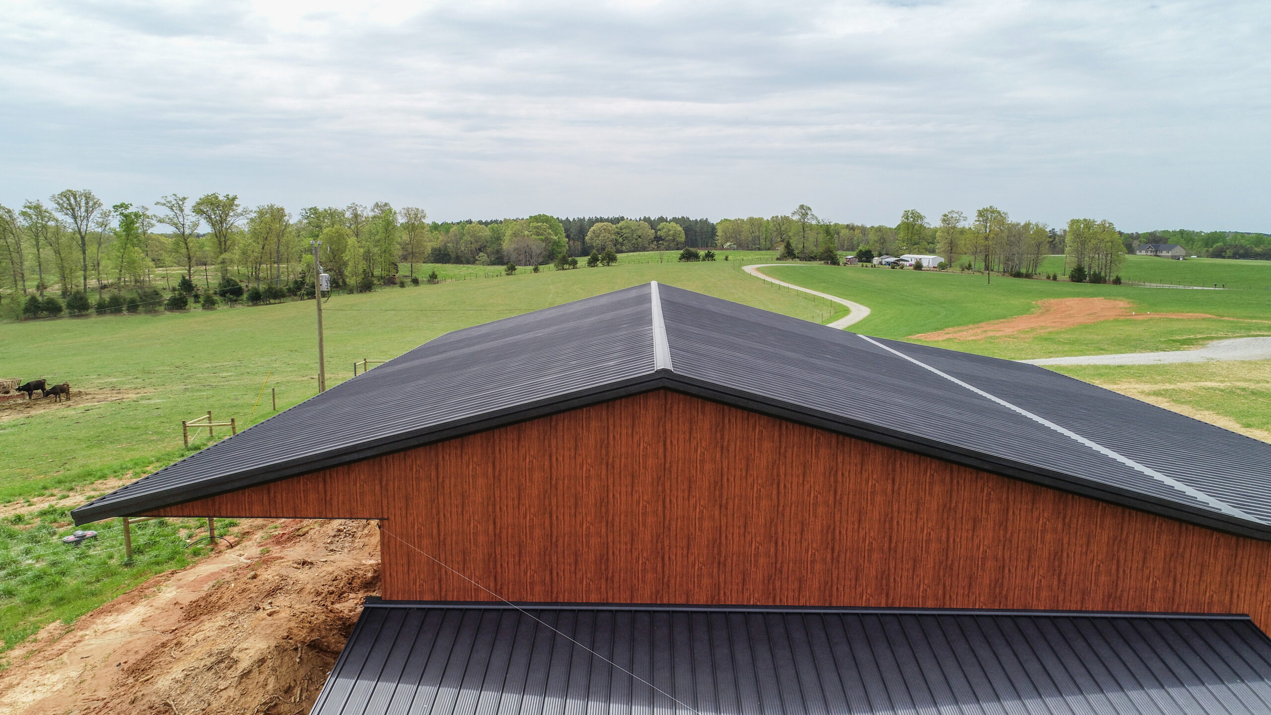 Manufacturer roof example showing dark metal panels, straight roof lines and a finished ridge on a wood-clad building